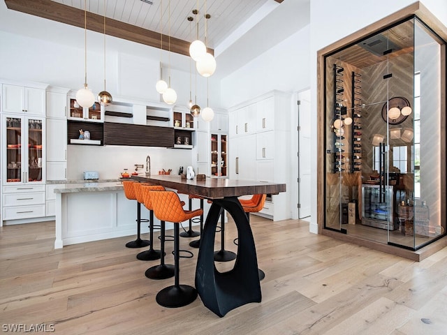 kitchen featuring white cabinets, hanging light fixtures, light hardwood / wood-style floors, and a breakfast bar