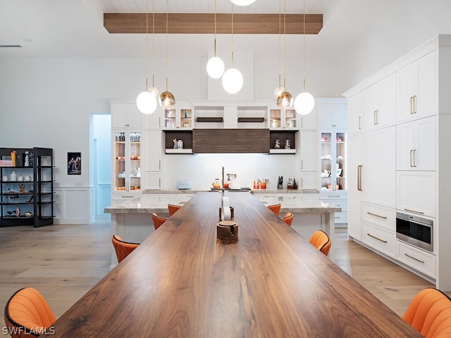 kitchen featuring pendant lighting, a kitchen breakfast bar, light hardwood / wood-style flooring, white cabinetry, and a center island