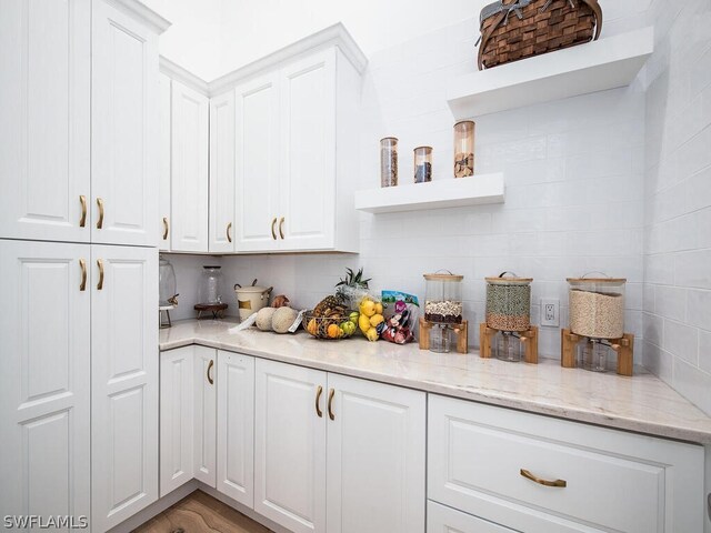 kitchen featuring white cabinets, light hardwood / wood-style floors, and light stone countertops