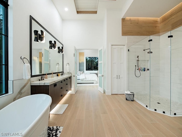 bathroom featuring hardwood / wood-style flooring, vanity, a towering ceiling, shower with separate bathtub, and a healthy amount of sunlight