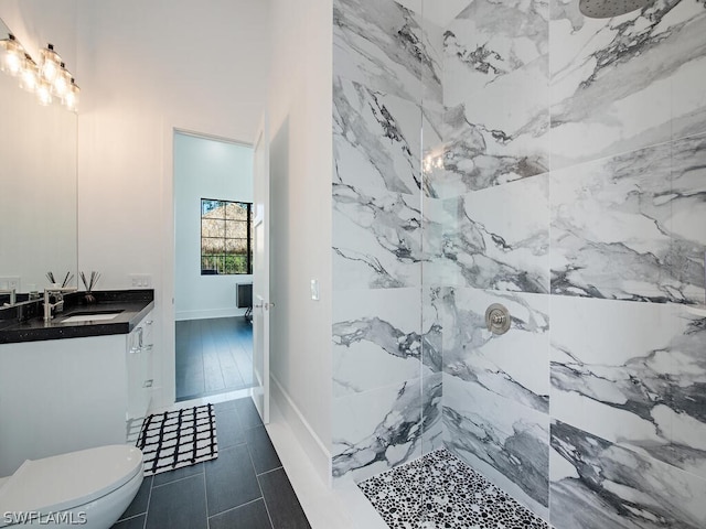 bathroom with oversized vanity, toilet, tiled shower, and tile flooring