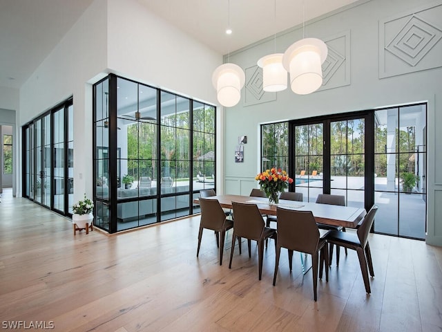 dining area with a high ceiling, a chandelier, and light hardwood / wood-style floors