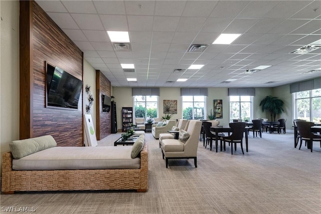 living room featuring a drop ceiling and light colored carpet