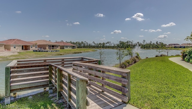 dock area with a lawn and a water view