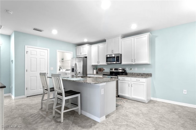 kitchen with white cabinets, a center island with sink, and stainless steel appliances