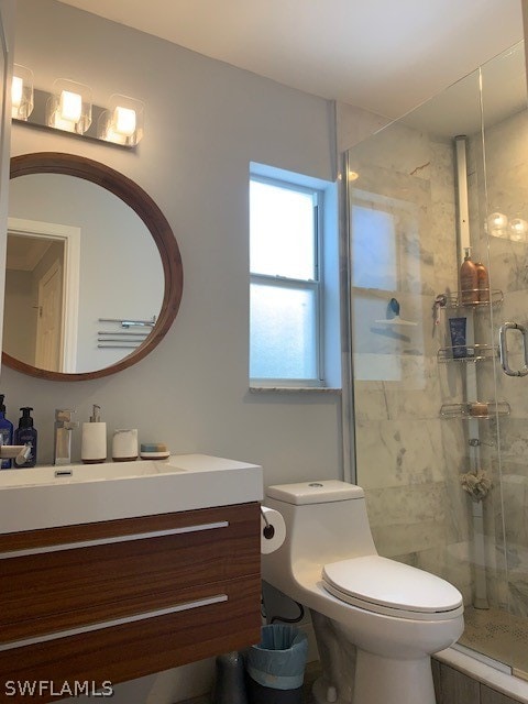 bathroom featuring toilet, an enclosed shower, and vanity