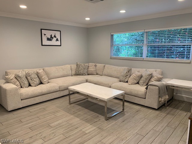 living room with ornamental molding and light hardwood / wood-style flooring