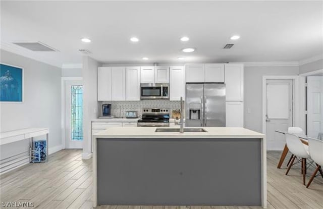 kitchen with a center island with sink, stainless steel appliances, and white cabinetry