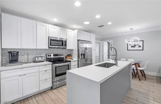 kitchen featuring pendant lighting, appliances with stainless steel finishes, sink, a kitchen island with sink, and an inviting chandelier