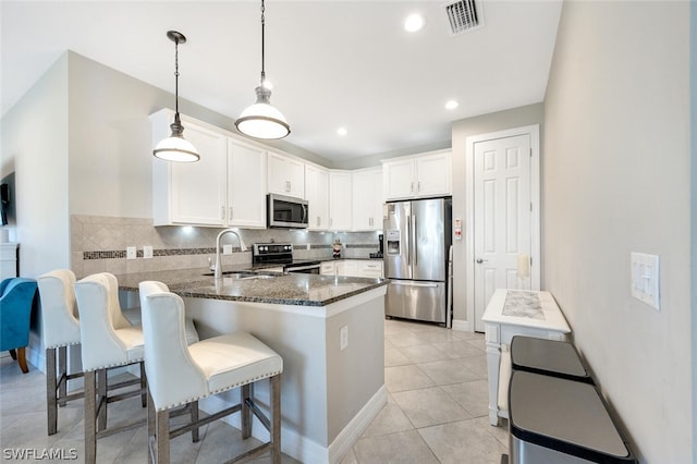 kitchen featuring stainless steel appliances, dark stone counters, backsplash, hanging light fixtures, and sink