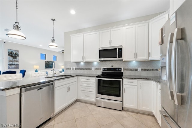 kitchen with white cabinets, stainless steel appliances, decorative light fixtures, and dark stone countertops