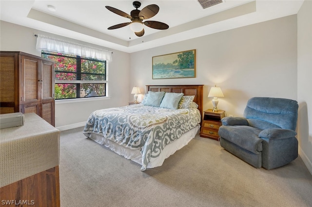 carpeted bedroom featuring a tray ceiling and ceiling fan