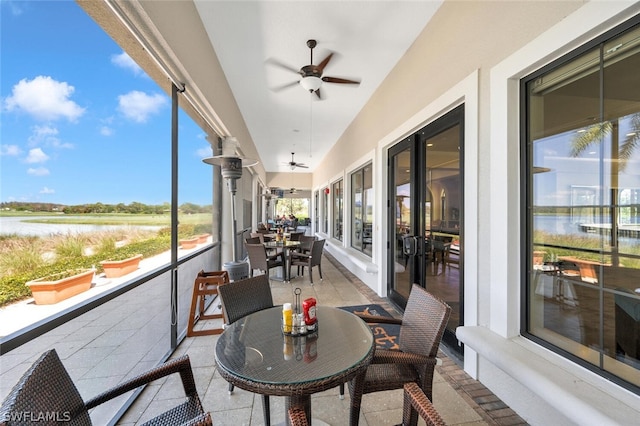 sunroom featuring a healthy amount of sunlight, ceiling fan, and a water view