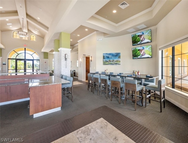 kitchen with high vaulted ceiling, beam ceiling, and dark colored carpet