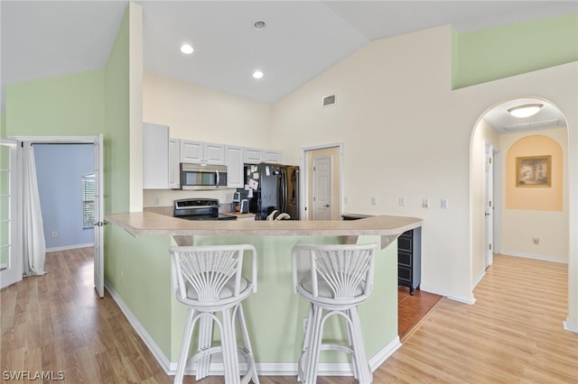 kitchen featuring electric range oven, a breakfast bar area, light wood-type flooring, and white cabinetry