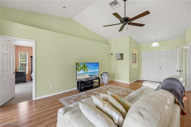 living room with ceiling fan, light wood-type flooring, and vaulted ceiling