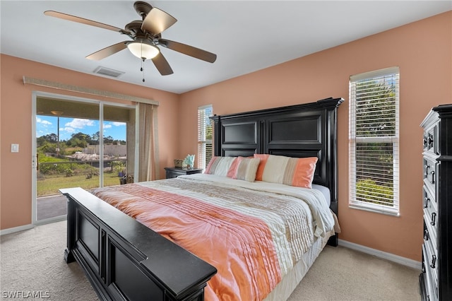 bedroom with ceiling fan, access to exterior, light carpet, and multiple windows