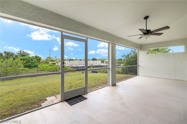 unfurnished sunroom featuring ceiling fan and a wealth of natural light