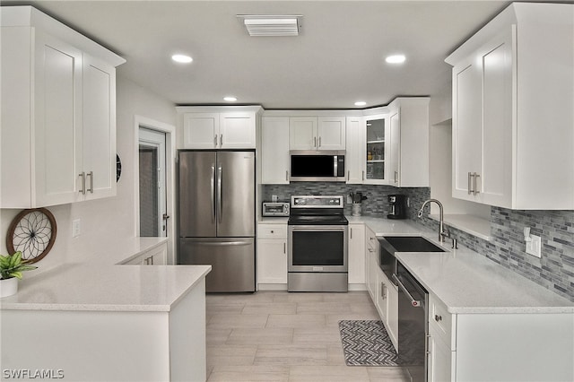 kitchen with light tile flooring, tasteful backsplash, stainless steel appliances, sink, and white cabinetry