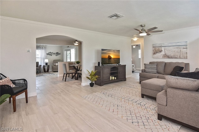 living room featuring ornamental molding, ceiling fan, and light wood-type flooring