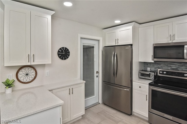 kitchen with appliances with stainless steel finishes, white cabinetry, backsplash, and light stone countertops