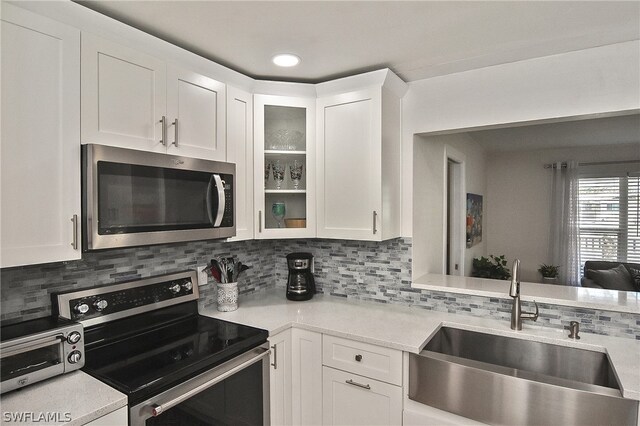 kitchen with white cabinets, backsplash, sink, and stainless steel appliances