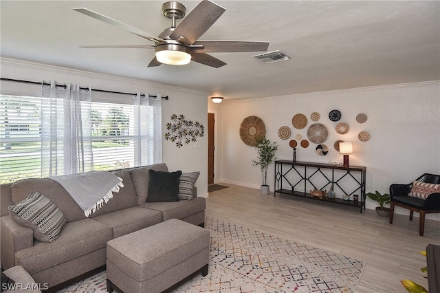 living room with light hardwood / wood-style floors, ceiling fan, and ornamental molding