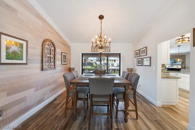 dining space featuring a chandelier, wood walls, light hardwood / wood-style floors, and crown molding