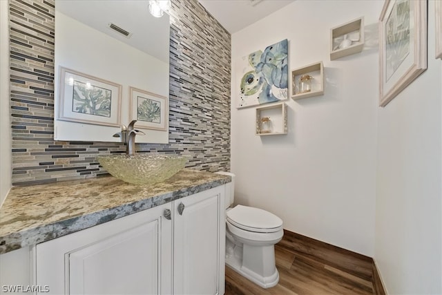 bathroom featuring backsplash, vanity with extensive cabinet space, toilet, and wood-type flooring