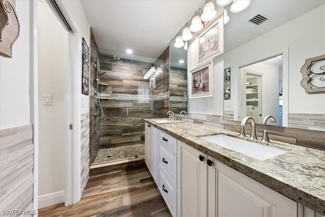 bathroom featuring tasteful backsplash, hardwood / wood-style floors, tiled shower, and double sink vanity