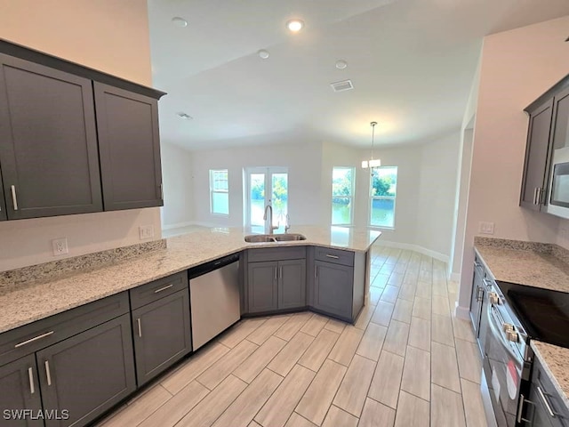 kitchen featuring kitchen peninsula, light stone countertops, light wood-type flooring, sink, and stainless steel appliances