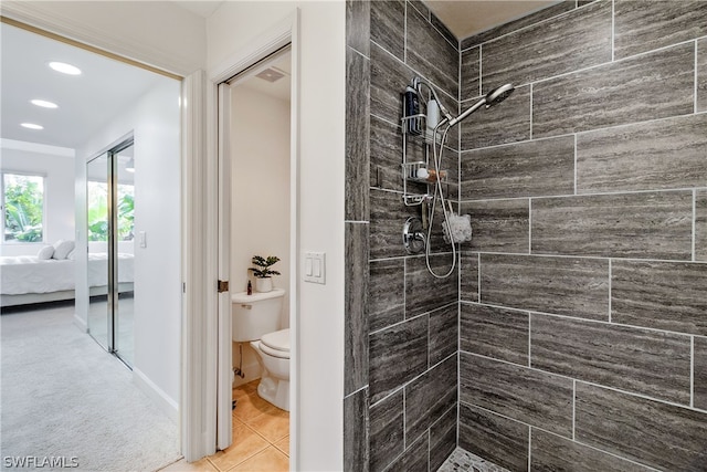 bathroom with tile flooring, tiled shower, and toilet