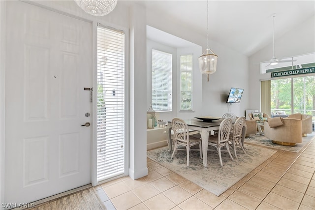 tiled dining space featuring ceiling fan and vaulted ceiling