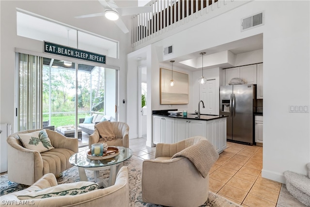 tiled living room with ceiling fan and a high ceiling