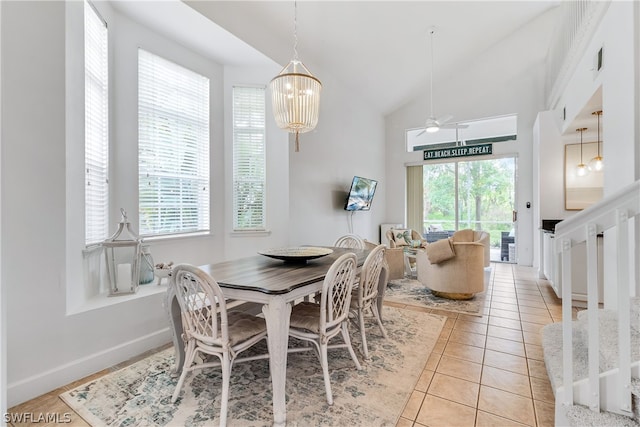dining area featuring visible vents, light tile patterned floors, high vaulted ceiling, baseboards, and ceiling fan with notable chandelier
