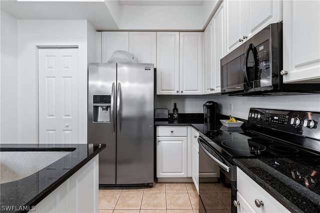 kitchen featuring light tile floors, white cabinetry, dark stone countertops, and black appliances