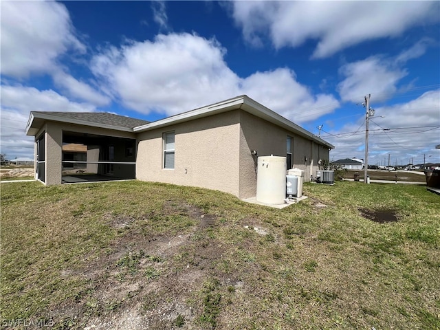 view of side of property with a lawn and central AC