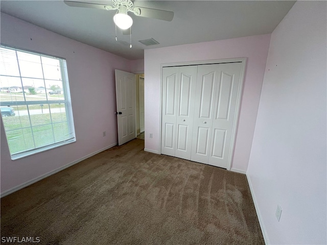 unfurnished bedroom with a closet, dark carpet, and ceiling fan