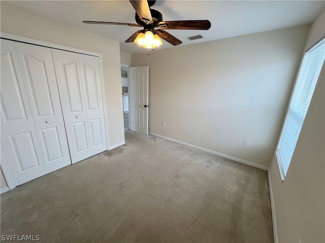 unfurnished bedroom featuring a closet, light carpet, and ceiling fan