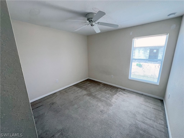 empty room featuring ceiling fan and dark colored carpet