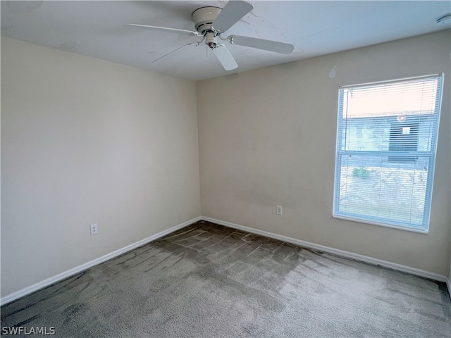 spare room with ceiling fan and dark colored carpet