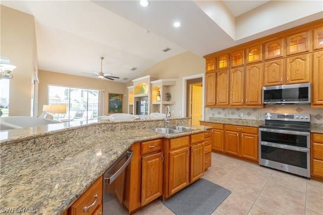 kitchen featuring ceiling fan, appliances with stainless steel finishes, sink, light stone counters, and tasteful backsplash