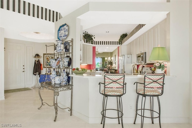 kitchen with sink, kitchen peninsula, appliances with stainless steel finishes, and a kitchen bar