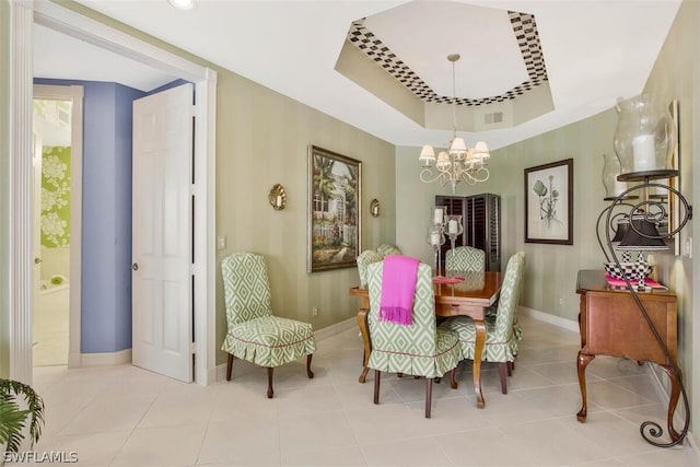 dining area with light tile patterned flooring, a chandelier, and a tray ceiling