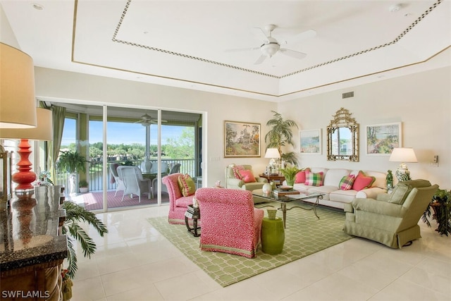 tiled living room with ceiling fan and a raised ceiling