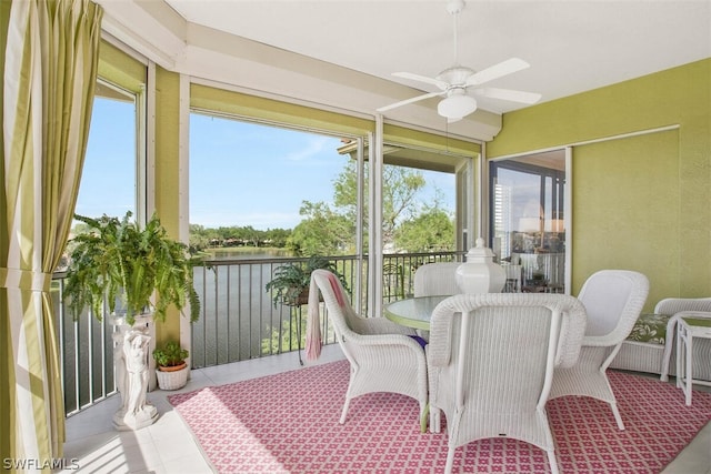 sunroom featuring ceiling fan and a water view