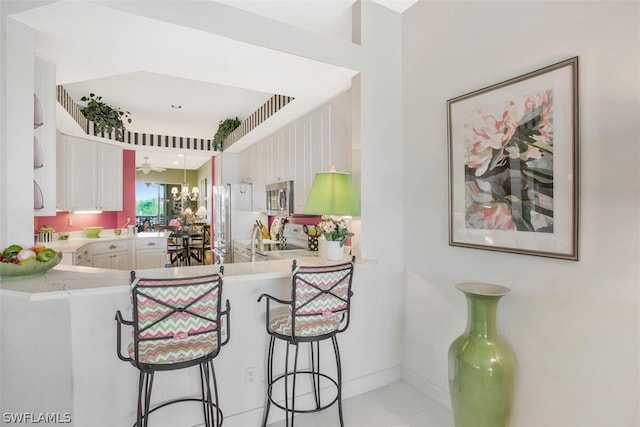 kitchen with kitchen peninsula, white cabinets, a breakfast bar area, and appliances with stainless steel finishes