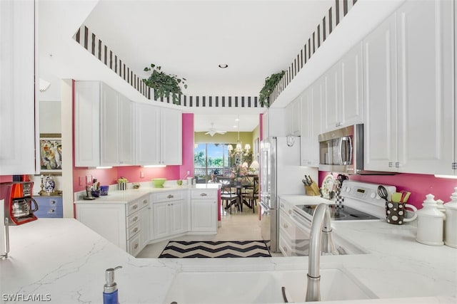 kitchen featuring kitchen peninsula, white cabinetry, light stone countertops, and appliances with stainless steel finishes