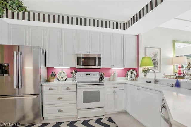 kitchen with light stone counters, white cabinets, appliances with stainless steel finishes, and sink