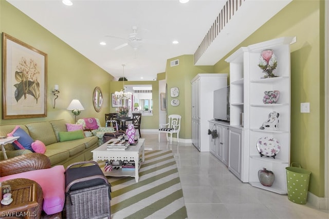 tiled living room with ceiling fan with notable chandelier